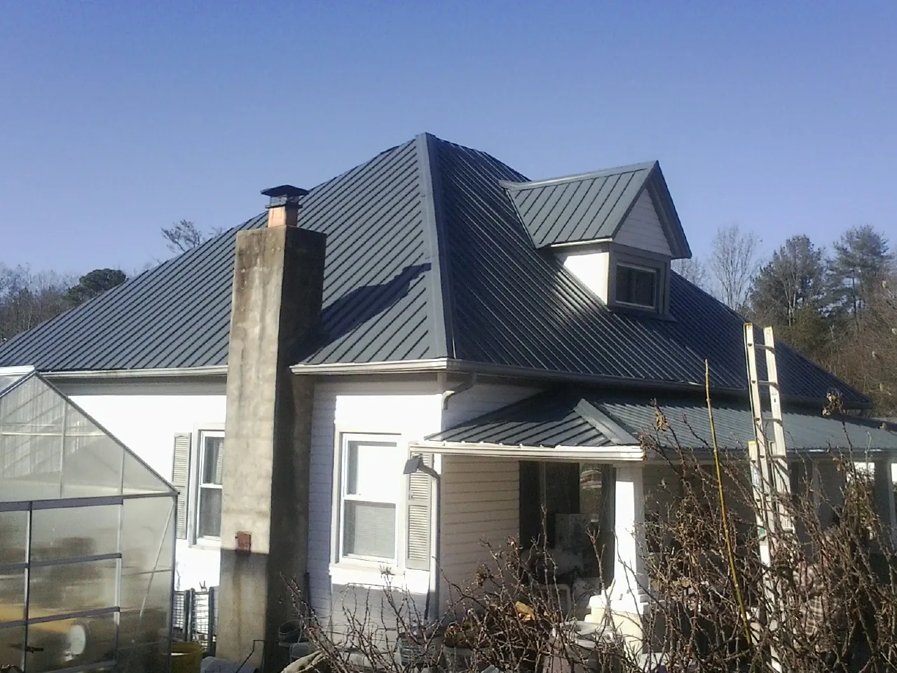Dark blue standing seam metal roof on a white farmhouse with dormer — Slate & Tile Roof Repair by Roofing Brothers in Tallmadge