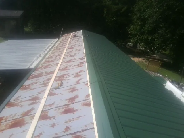Old rusted panels beside newly installed green metal roofing — Wind Damage Roof Repair by Roofing Brothers in Tallmadge