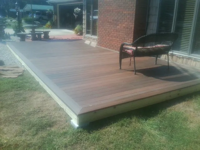 New wood deck and wicker chair beside a brick house in Tallmadge