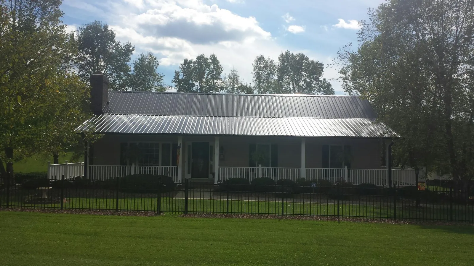 Gray metal roof on a brick ranch with a full width front porch — Gutter Guard Installation work by our crew in Tallmadge
