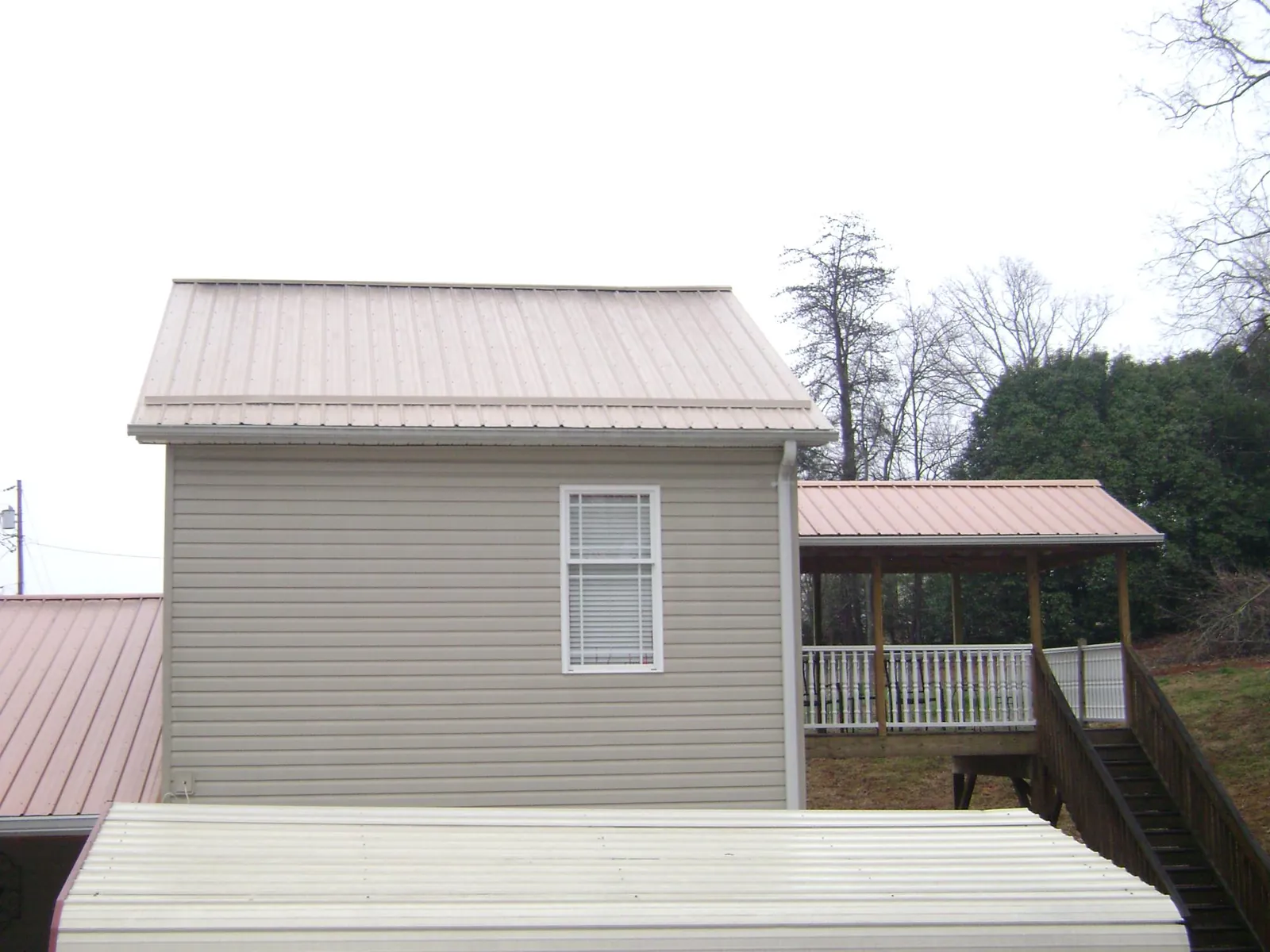 Tan metal roofs on a two story addition and attached porch, from a Roof Replacement job in Tallmadge