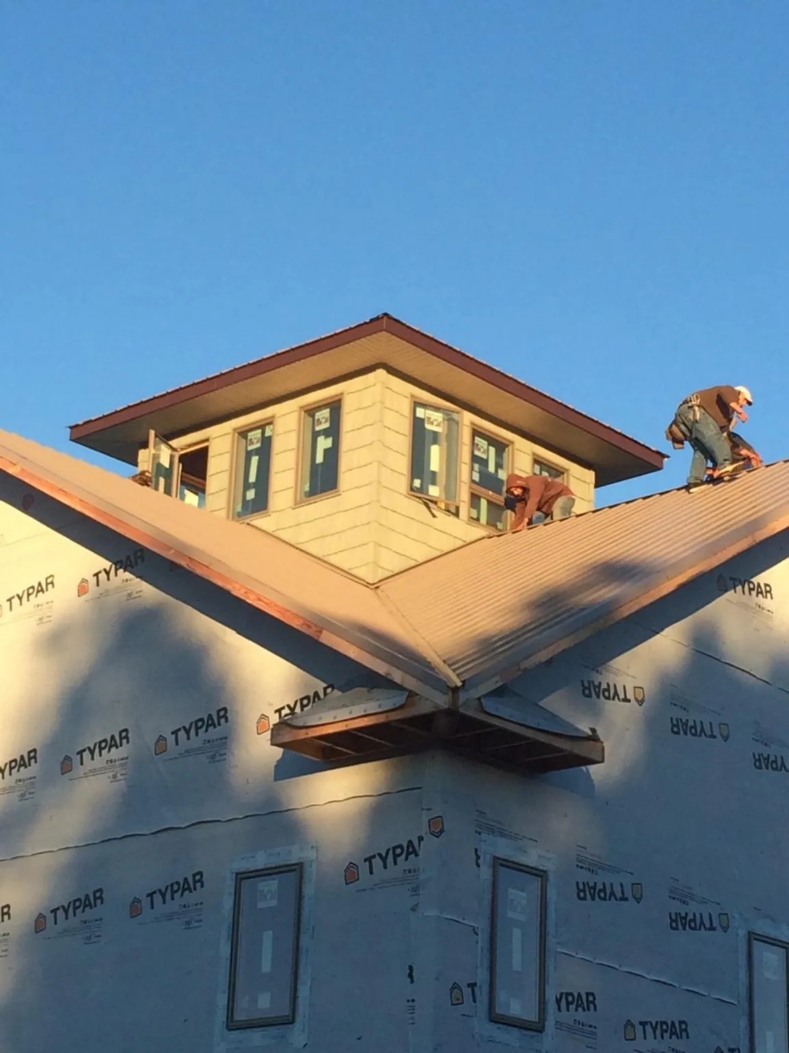 Roofers working around a rooftop cupola on a new metal roof at sunset — Roof Waterproofing in Tallmadge by Roofing Brothers